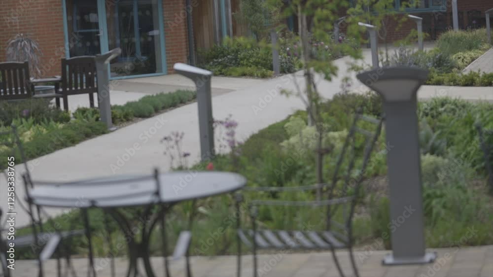 A black metal table with four chairs around it. The chairs are empty. The table is in a park A black metal table with four chairs around it. The chairs are empty. The table is in a park