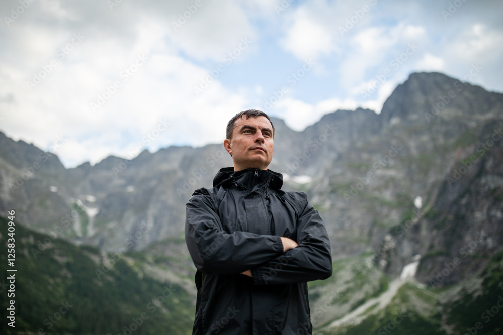 Portrait of handsome man standing against beautiful landscape with mountains and rocks
