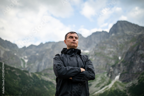 Portrait of handsome man standing against beautiful landscape with mountains and rocks
