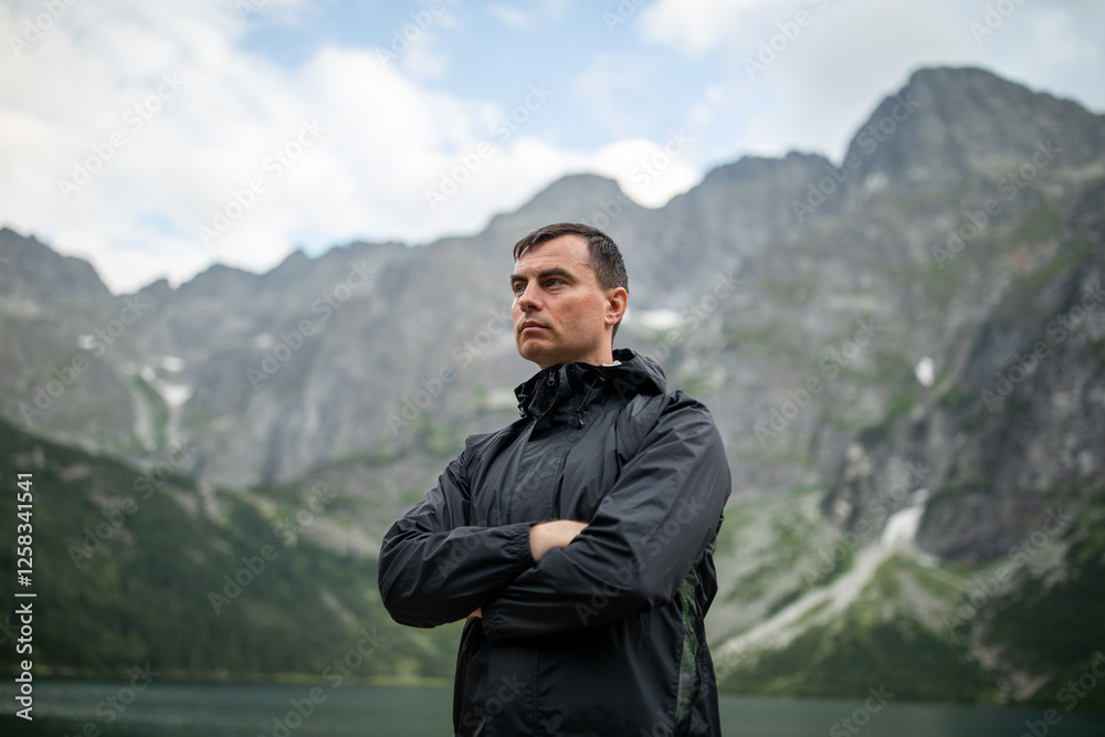 Portrait of handsome man standing against beautiful landscape with mountains and rocks