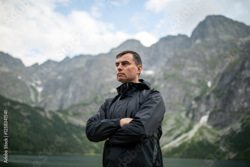 Obraz na płótnie Portrait of handsome man standing against beautiful landscape with mountains and rocks w salonie