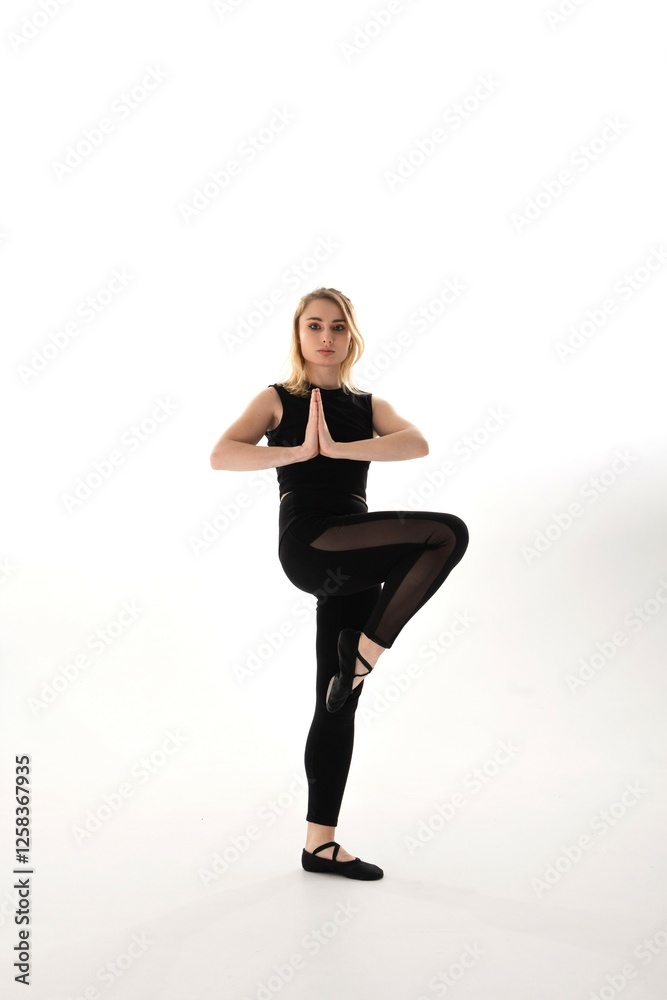 Dancer in black attire performs a graceful pose on a white background during a studio session Dancer in black attire performs a graceful pose on a white background during a studio session