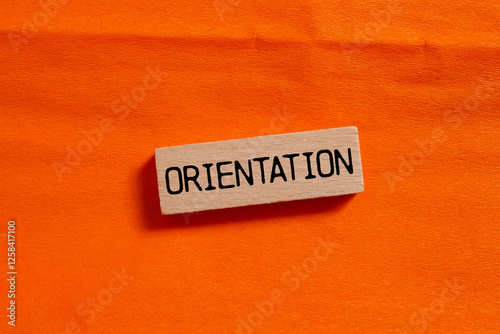 Orientation message written on wooden block on orange background. Conceptual orientation symbol. Copy space.
