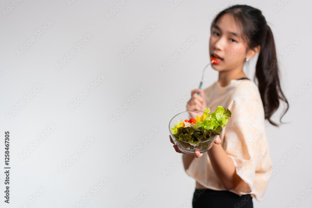 Portrait of a happy playful Asian girl eating fresh salad from a glass bowl after workout at home. Young lady Enjoying Healthy Nutrition And Organic Food, Having Vegetarian Meal Portrait of a happy playful Asian girl eating fresh salad from a glass bowl after workout at home. Young lady Enjoying Healthy Nutrition And Organic Food, Having Vegetarian Meal