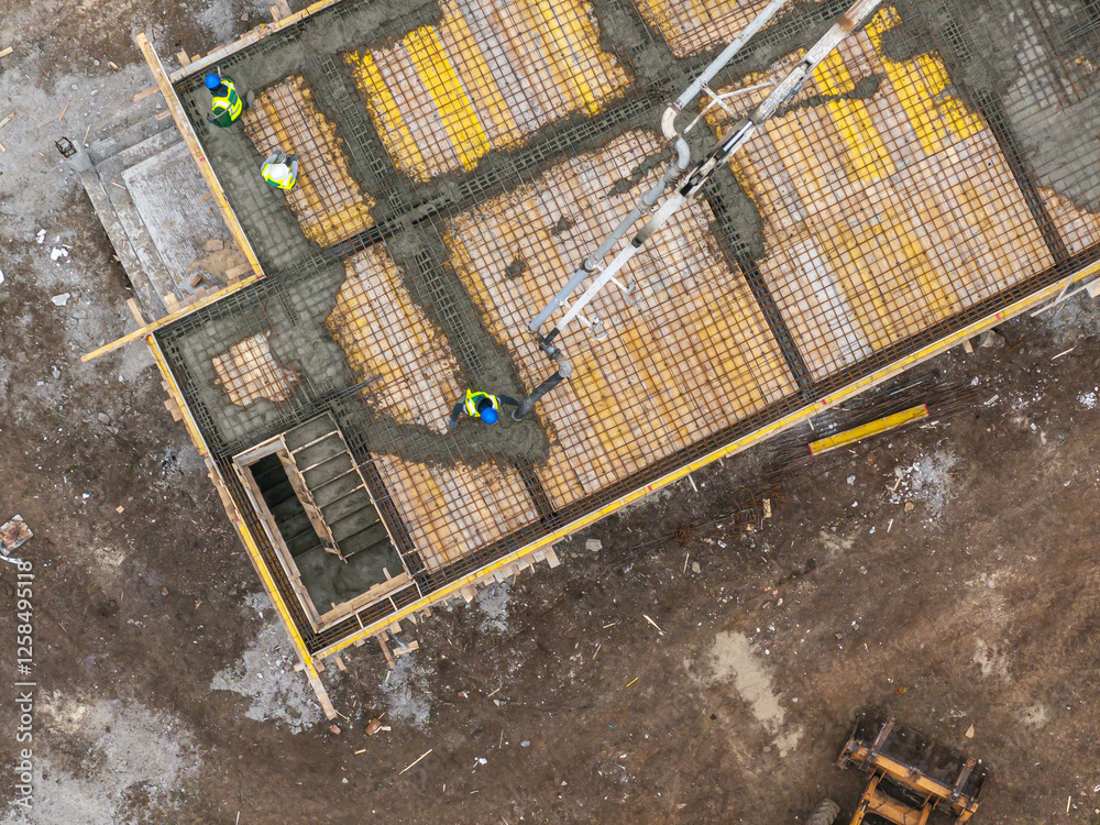 Aerial view of a construction site with workers pouring concrete using a pump truck, highlighting industrial development and teamwork in the building process. Residential construction industry.