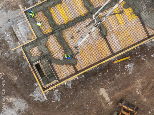 Obraz na płótnie Aerial view of a construction site with workers pouring concrete using a pump truck, highlighting industrial development and teamwork in the building process. Residential construction industry. w salonie
