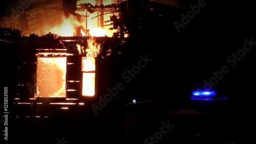 The house is on fire from inside and outside with large flames, flaming doors and windows. The great fiery misfortune of people. Fire rescue at night of the building.