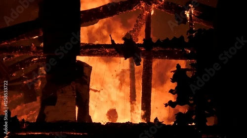 The house is on fire from inside and outside with large flames, flaming doors and windows. The great fiery misfortune of people. Fire rescue at night of the building.