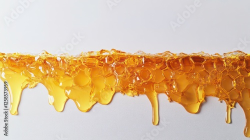 A tight shot of a honeycomb against a pristine white backdrop, with golden honey trickling down its edge