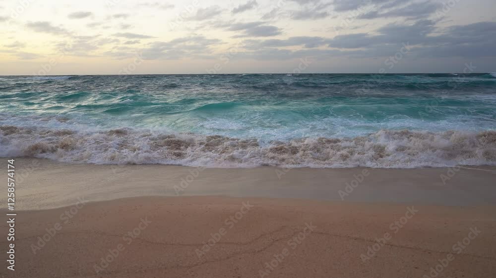 A tranquil beach scene at sunset in Hawaii, featuring turquoise water, golden skies, scattered clouds, and the motion of waves on the sandy shore. A tranquil beach scene at sunset in Hawaii, featuring turquoise water, golden skies, scattered clouds, and the motion of waves on the sandy shore.