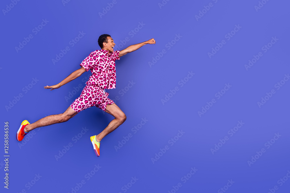 Energetic young man dresses in stylish leopard pink outfit leaps against a bold purple background Energetic young man dresses in stylish leopard pink outfit leaps against a bold purple background
