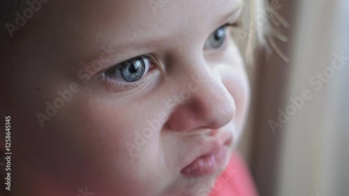 Close-up of young girl scrunching nose and wiggling nostrils with an intense expression. Blue eyes, fair skin, emotional reaction, curious look. Child face macro, funny kid, natural light