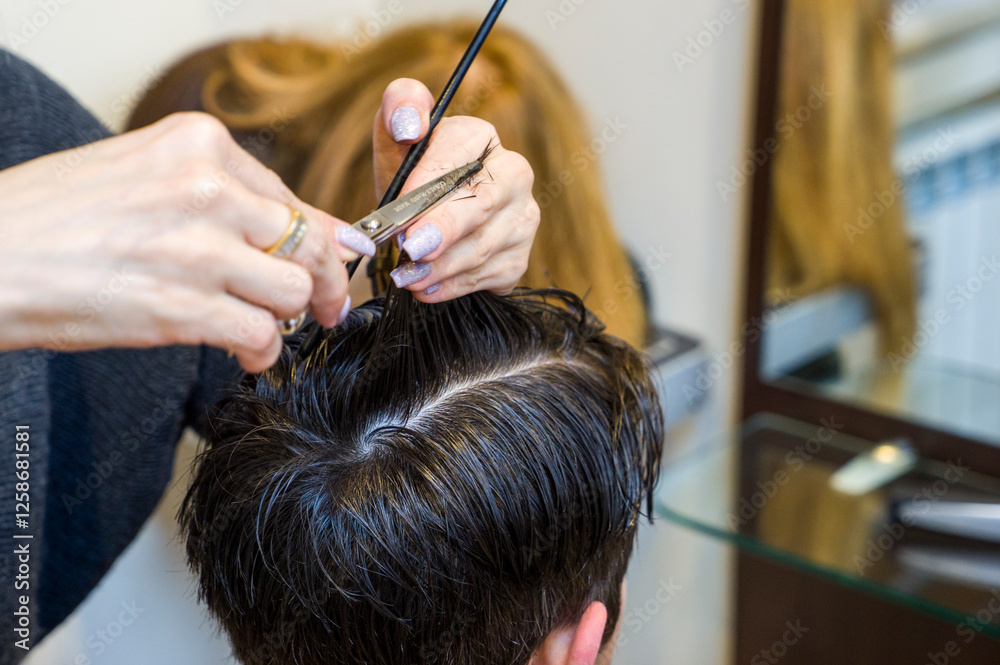 Naklejka premium men's hairstyling and haircutting with hair clipper in a barber shop or hair salon,close up
