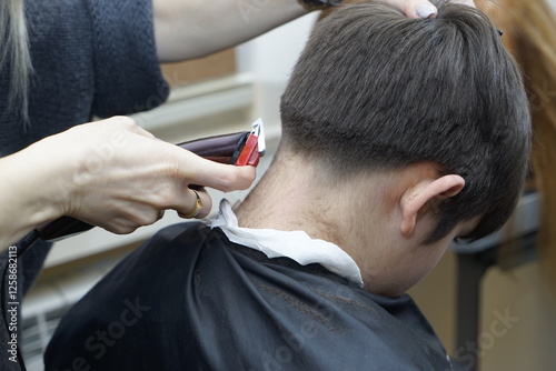 men's hairstyling and haircutting with hair clipper in a barber shop or hair salon,close up