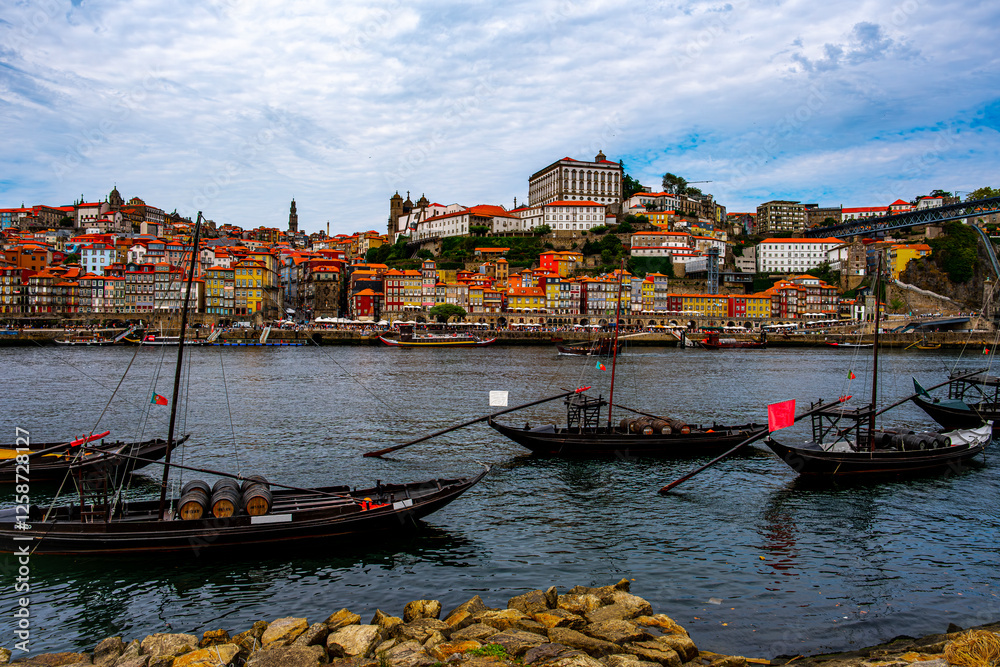 Obraz premium Ships calmly floating on the water with barrels on board, in the background a view of the beautiful city of Porto