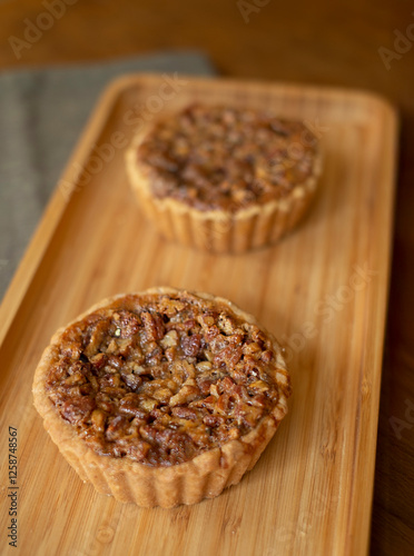 Tartaletas de nuez caramelizada sobre tabla de bambú en composición minimalista
