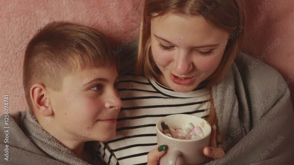Sibling siblings huddling closely, sipping marshmallow-topped hot chocolate, snuggling under soft blanket during intimate winter bonding moment