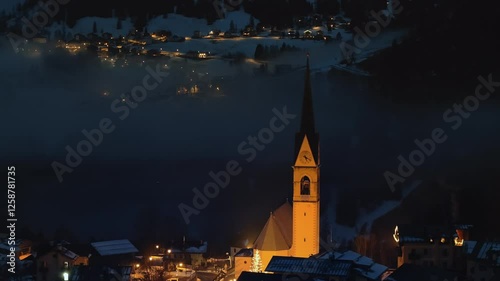 Aerial drone view of the San Lorenzo Church illuminated at night in the Selva di Cadore comune in Dolomites, Italy photo