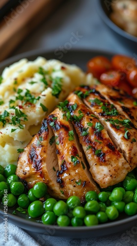 Grilled chicken served with mashed potatoes and green peas on a plate at a co...