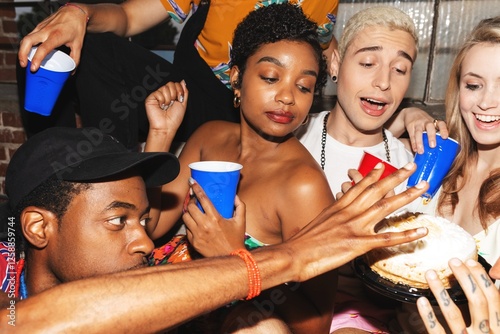 Sticker Group of friends at a party, holding drinks, reaching for a pie