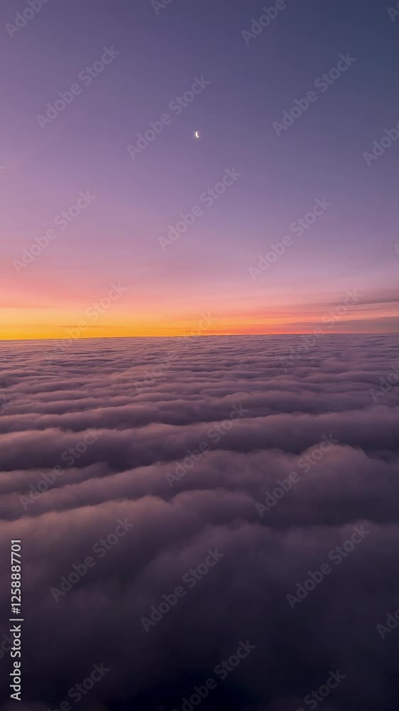 Plane journey above the clouds: crescent moon at sunset on dreamy cloud sea. Ethereal purple and gold cloudscape. Vertical footage of high altitude flight over cloud layer. Plane journey above the clouds: crescent moon at sunset on dreamy cloud sea. Ethereal purple and gold cloudscape. Vertical footage of high altitude flight over cloud layer.
