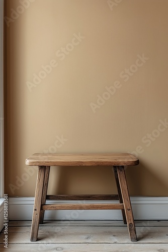 Simple wooden stool against a beige wall in a cozy interior setting with natu...