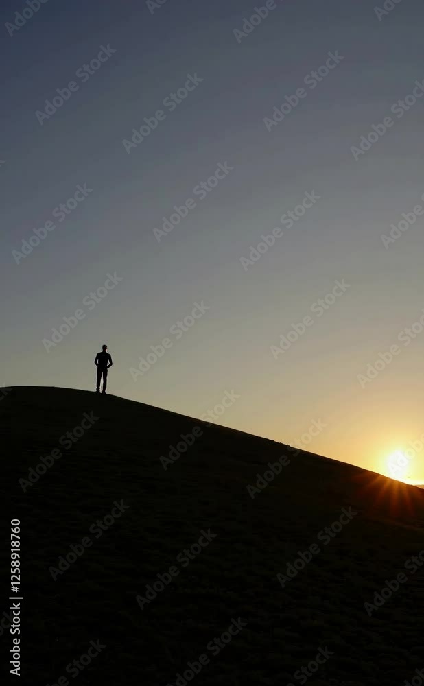 Silhouette of a person on a hilltop against a vibrant sunset sky Silhouette of a person on a hilltop against a vibrant sunset sky