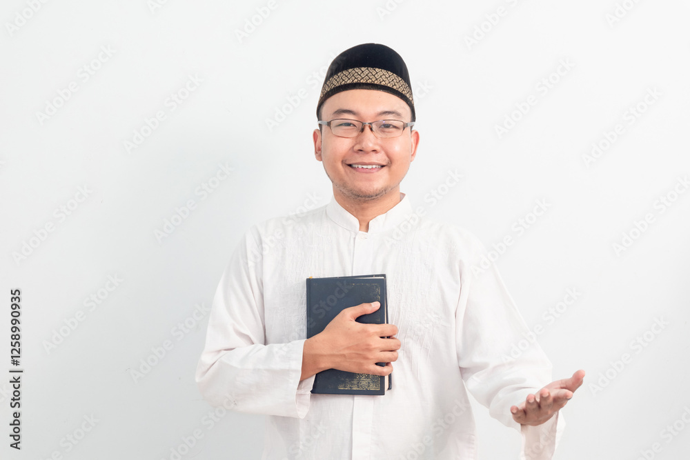 Asian Muslim man wearing white clothes welcoming and holding quran during Ramadan Eid Al Fitr and eid adha days celebration isolated white background. Islamic celebration concept.. Asian Muslim man wearing white clothes welcoming and holding quran during Ramadan Eid Al Fitr and eid adha days celebration isolated white background. Islamic celebration concept..
