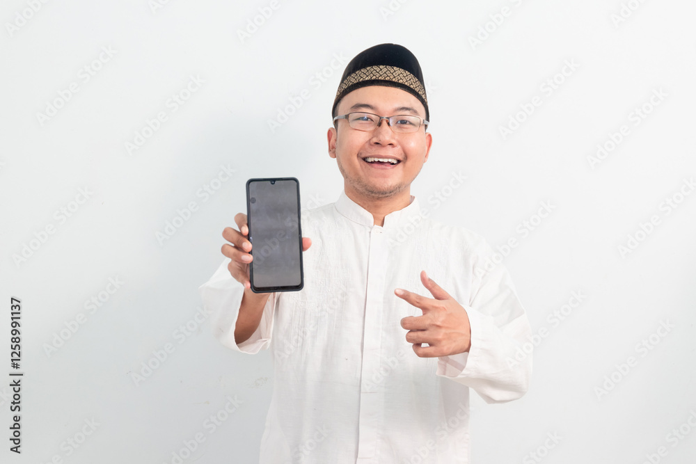 Asian Muslim man wearing white clothes smiling pointing phone pose, Ramadan Eid Al Fitr and eid adha days celebration isolated white background. Islamic celebration concept.. Asian Muslim man wearing white clothes smiling pointing phone pose, Ramadan Eid Al Fitr and eid adha days celebration isolated white background. Islamic celebration concept..