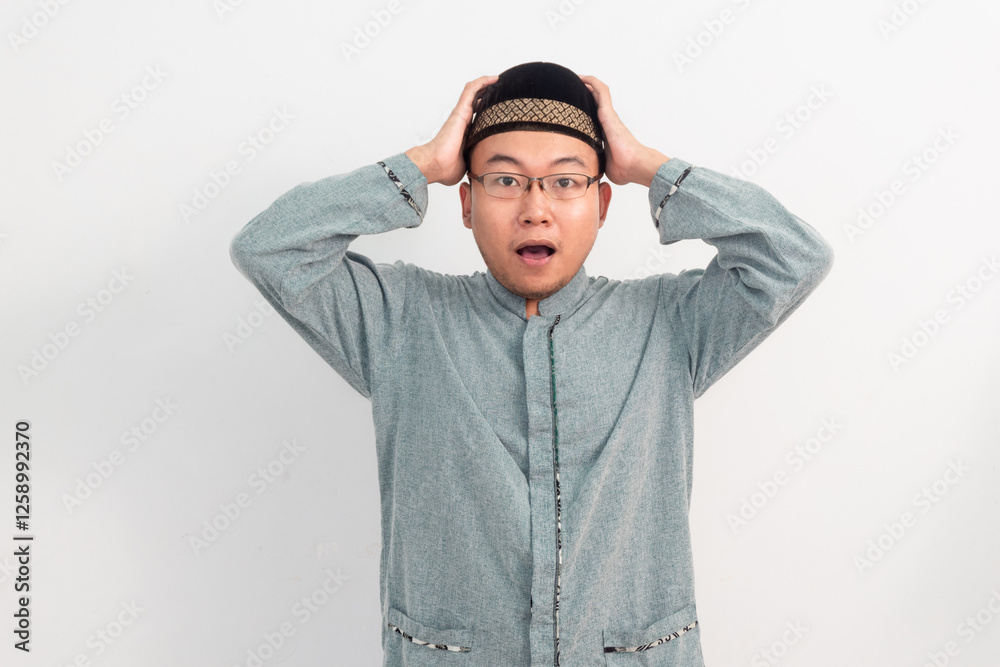 Surprised Asian Muslim man Shocked gesture in Ramadan Eid Al Fitr and eid adha days celebration isolated white background. Islamic celebration concept..