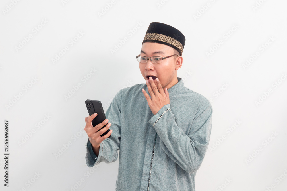 Surprised Asian Muslim man holding phone in Ramadan Eid Al Fitr and eid adha days celebration isolated white background. Islamic celebration concept.. Surprised Asian Muslim man holding phone in Ramadan Eid Al Fitr and eid adha days celebration isolated white background. Islamic celebration concept..