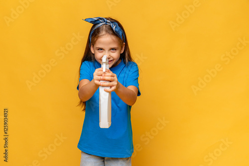 Happy emotional little girl in blue t-shirt holds household cleaning spray bottle and and pressing it. Enjoying household activities. Providing household help, copy space. High quality photo photo