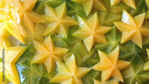 A seamless surface of starfruit slices, their unique star-shaped forms densely covering the entire frame with vibrant green-yellow hues.