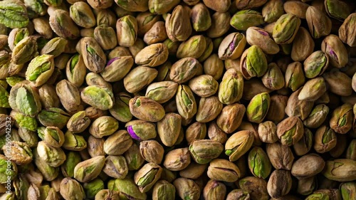 A seamless spread of whole pistachios in their shells, tightly packed together to fill the entire frame with a crunchy, earthy texture and warm green tones.