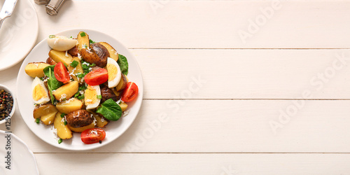 Plate of tasty potato salad with eggs and tomatoes on light background