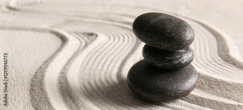 Canvas Print Stack of black stones on light sand with lines. Zen concept