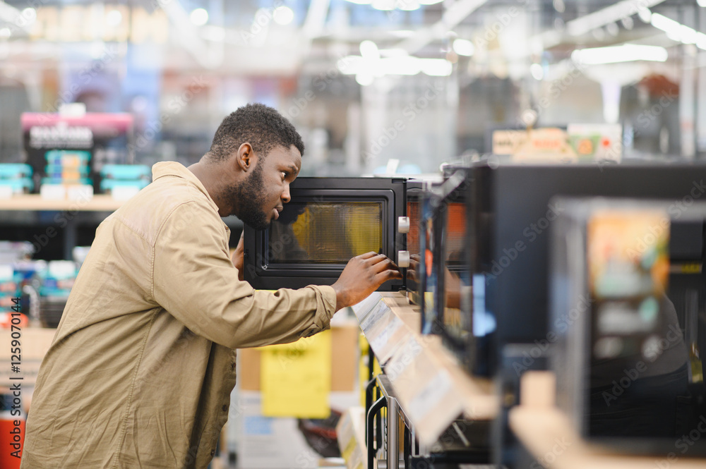 An African-American man is choosing a new microwave oven at an electronics store An African-American man is choosing a new microwave oven at an electronics store