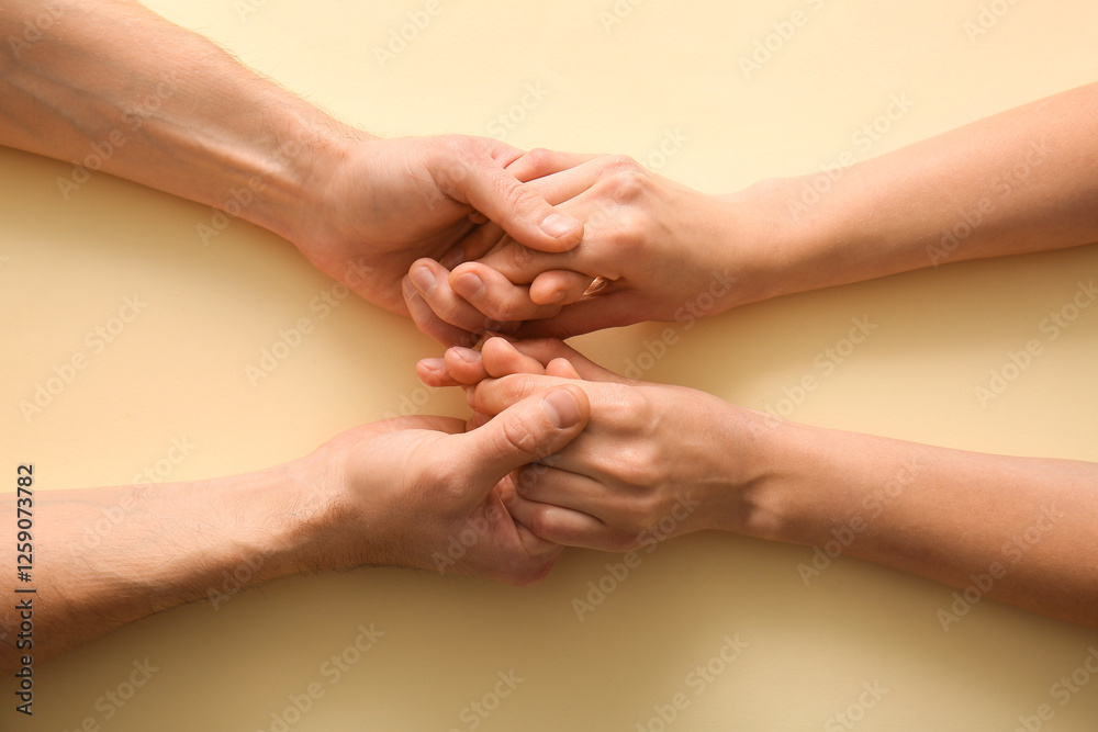 Fototapeta premium Couple holding hands on beige background, top view