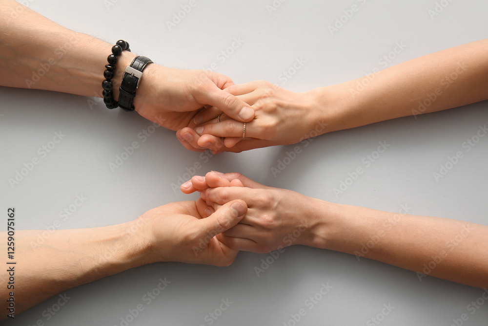 Fototapeta premium Couple holding hands on light background, top view
