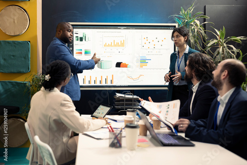 Accounting analysts studying sales trends and market demands to ensure business success, looking into data infographics in executive conference. Financial department team allocate funds.