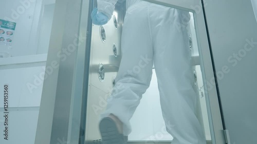 scientist in white protection suit walking through the air shower blowing disinfect machine to clean before working inside the lab, hygiene standard routine procedures before entering laboratory