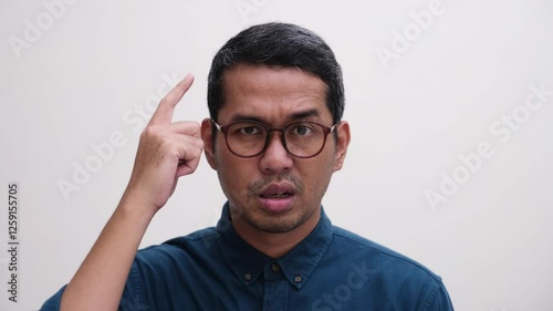 Close up shot of a man pointing his head with cynical face 