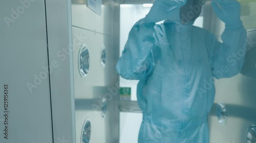 Laboratory scientist in blue protection suit walking through the air blowing disinfect machine to cleaning before working inside the lab, disinfection procedures before entering the laboratory