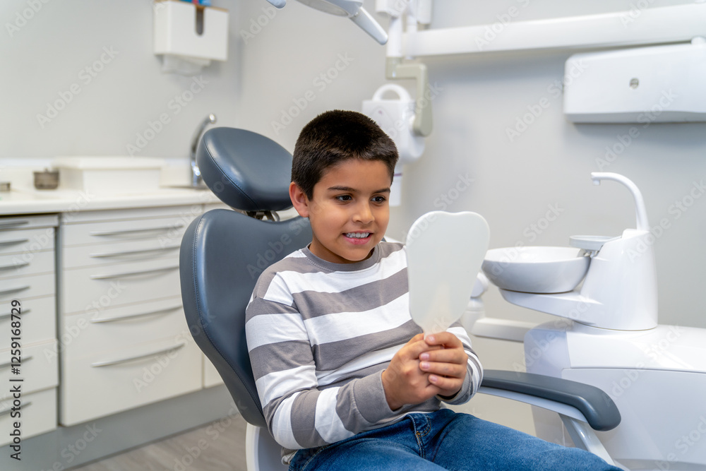 Young boy checking his teeth with a mirror at the dentist office Young boy checking his teeth with a mirror at the dentist office