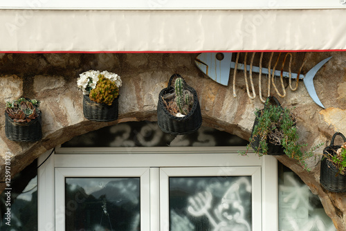 Rustic shopfront with plants and decorative fish, folded awning at a Mediterranean restaurant