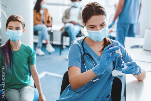 Vaccination And Immunization Concept. Woman nurse drawing medication out of vial before giving injection to patient. Young adolescent girl getting flu or flu antiviral vaccine at the medical centre photo