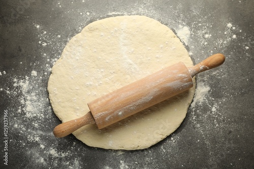 Fresh dough and rolling pin on grey table, top view