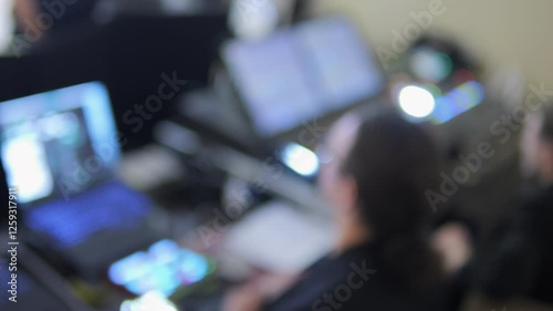 A blurry image of a group of people working on computers. Scene is focused and intense, as the people are all working on their laptops. The idea of the image is that of a busy office or workspace