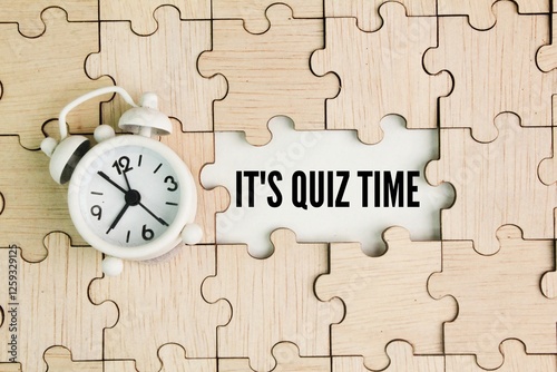 bell clock and wooden puzzle with the word It's Quiz Time. the concept of answering quizzes or quiz games