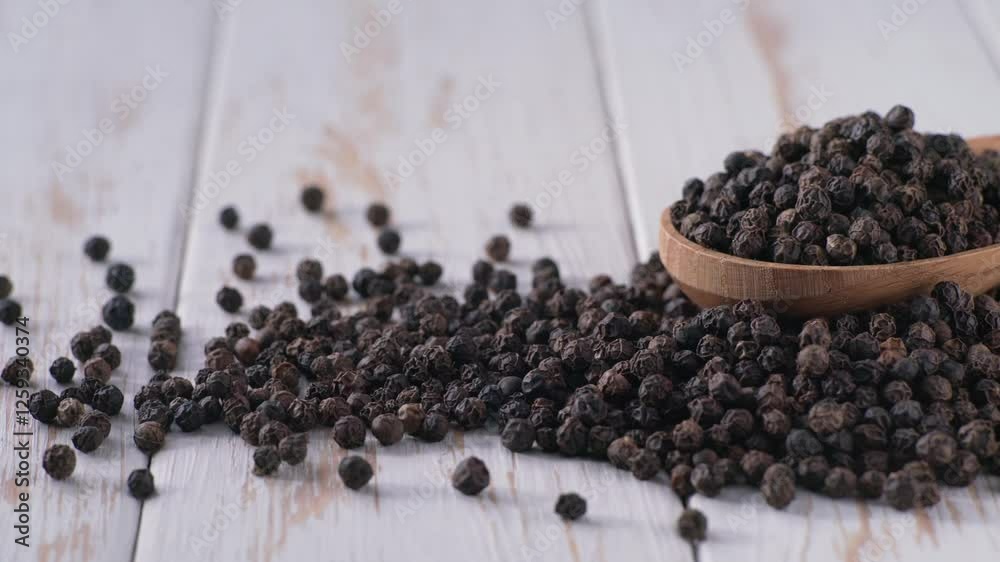Peppercorns or black pepper in a wooden spoon on a white wooden table. Peppercorns or black pepper in a wooden spoon on a white wooden table.